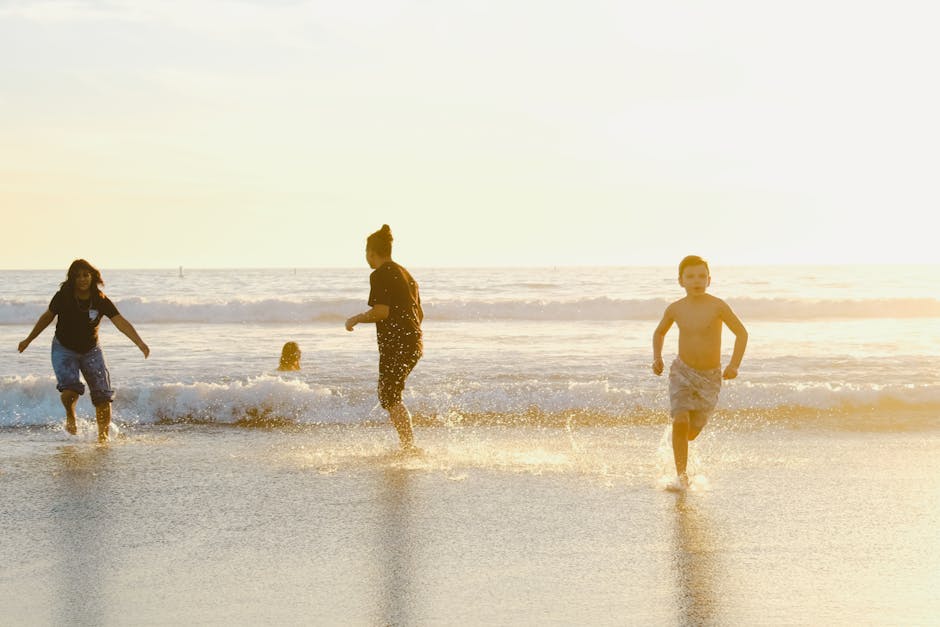 Youngsters run and play in the surf during a vibrant sunset at the beach.