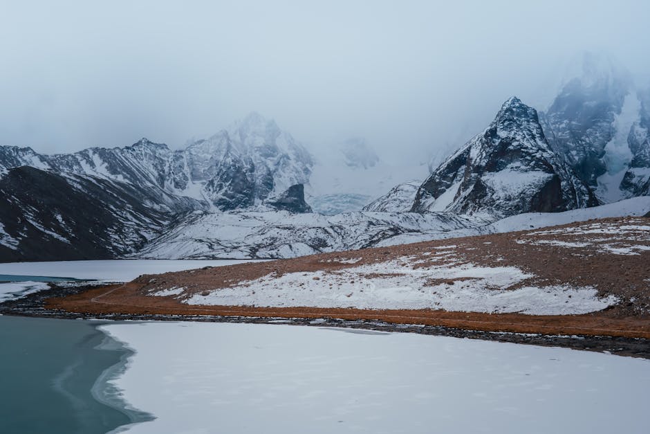 A breathtaking view of snowy mountain peaks and a frozen lake, showcasing the serene beauty of a glacier landscape.