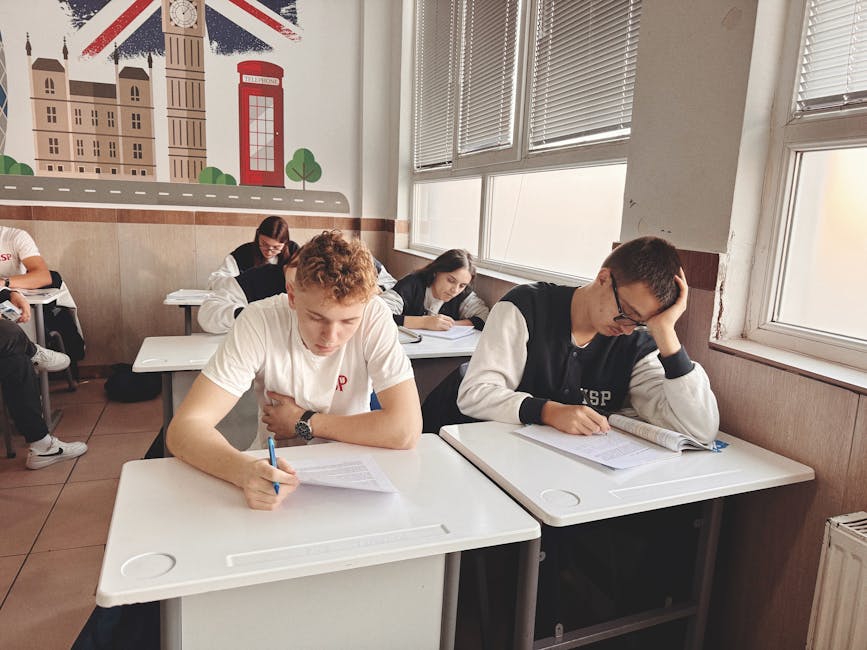 Students focused on their exams in a classroom featuring UK-themed wall art.