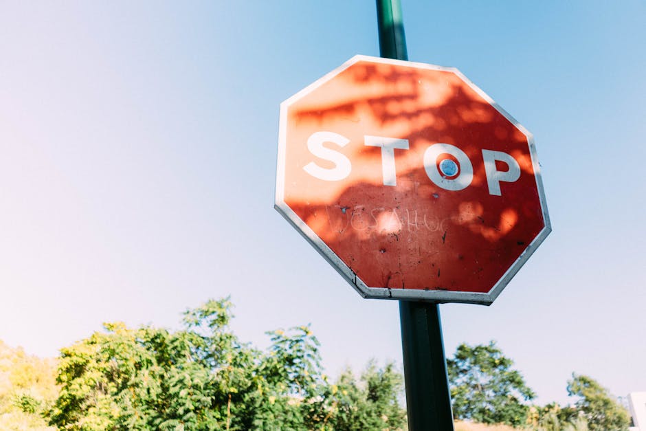 A red stop sign in Málaga, Spain, set against a clear blue sky and greenery, emphasizing safety and caution.